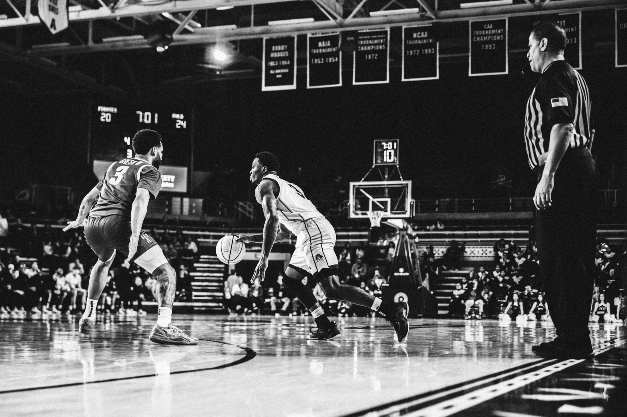 ECU and Temple players framed beneath the arena lights during game action